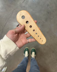 Hand holding a wooden tool with 8 holes in varied sizes for stripping herbs.
