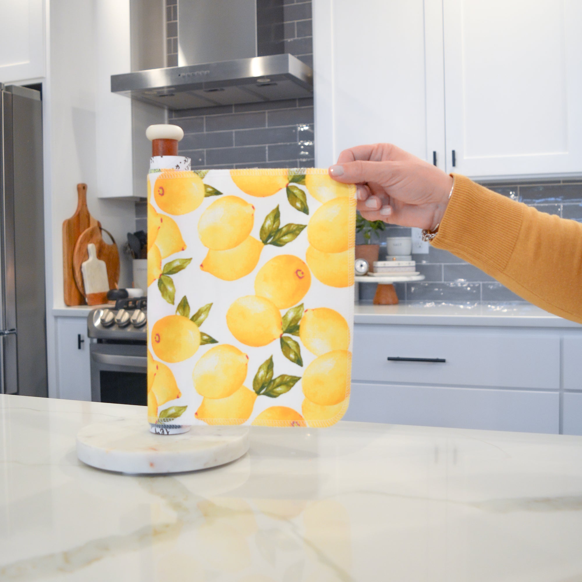 Shows a hand pulling off one UNpaper® Towel in the Marley's Favorites pack in the Vintage Lemons print. Marley's Monsters