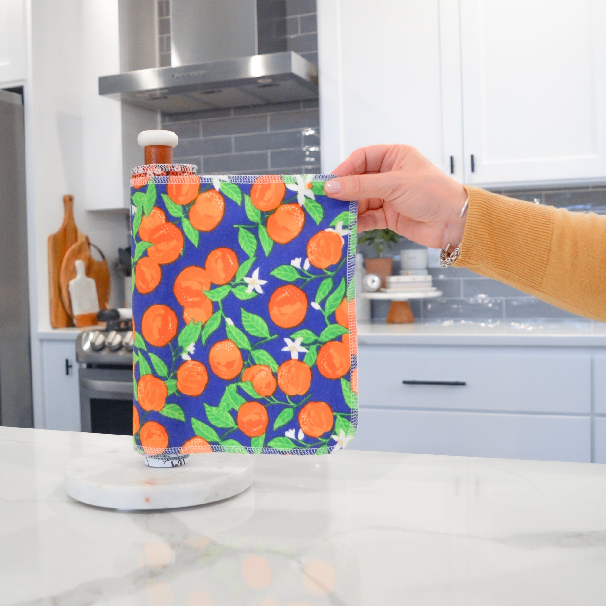 Shows a hand pulling off one UNpaper® Towel in the Marley's Favorites pack in the Oranges print. Marley's Monsters