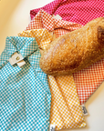 Colorful checkered bread bags with a loaf of bread on a white surface