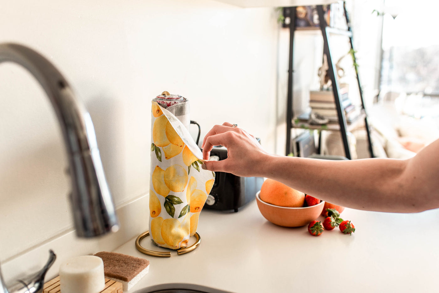 A hand pulling an UNpaper Towel from the roll in a kitchen
