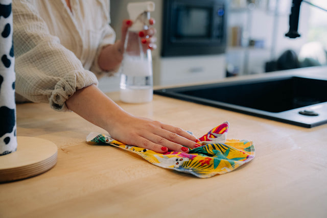 Hand wiping a counter with a bright printed UNpaper Towel
