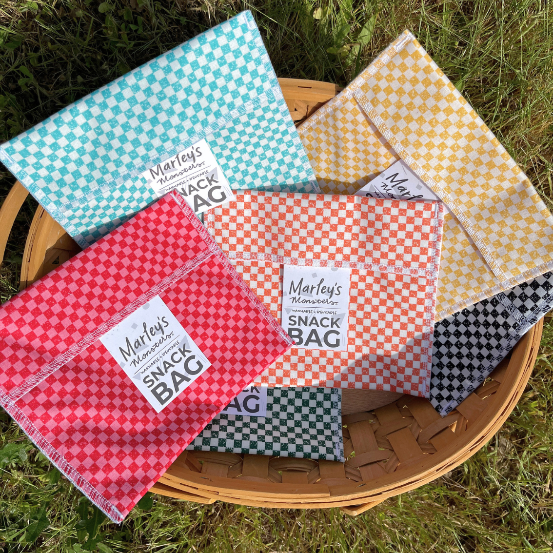 Colorful checkered snack bags with labels in a basket on grass