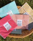 Colorful checkered snack bags with labels in a basket on grass