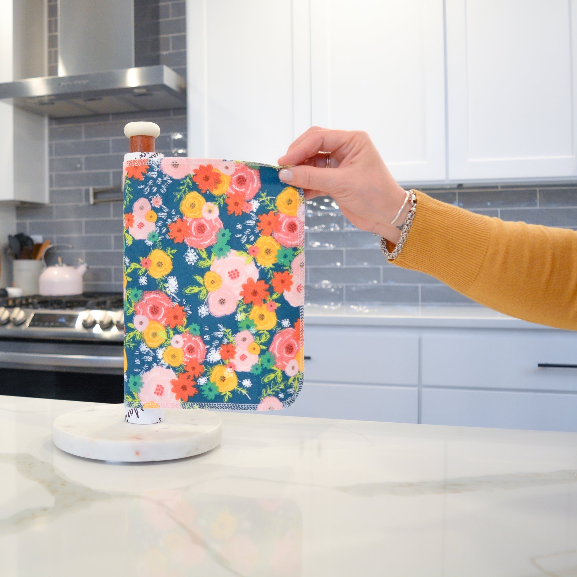 Shows a hand pulling off one UNpaper® Towel in the Marley&#39;s Favorites pack in the Fall Floral print. Marley&#39;s Monsters