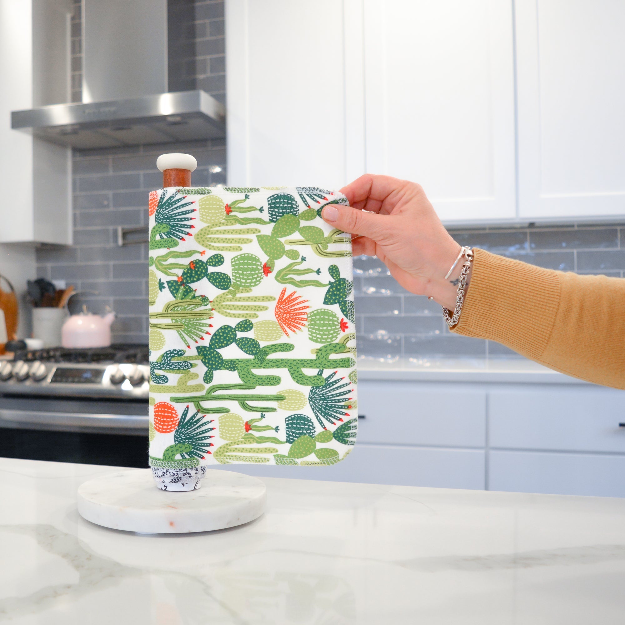 Shows a hand pulling off one UNpaper® Towel in the Marley&#39;s Favorites pack in the Cactus print. Marley&#39;s Monsters