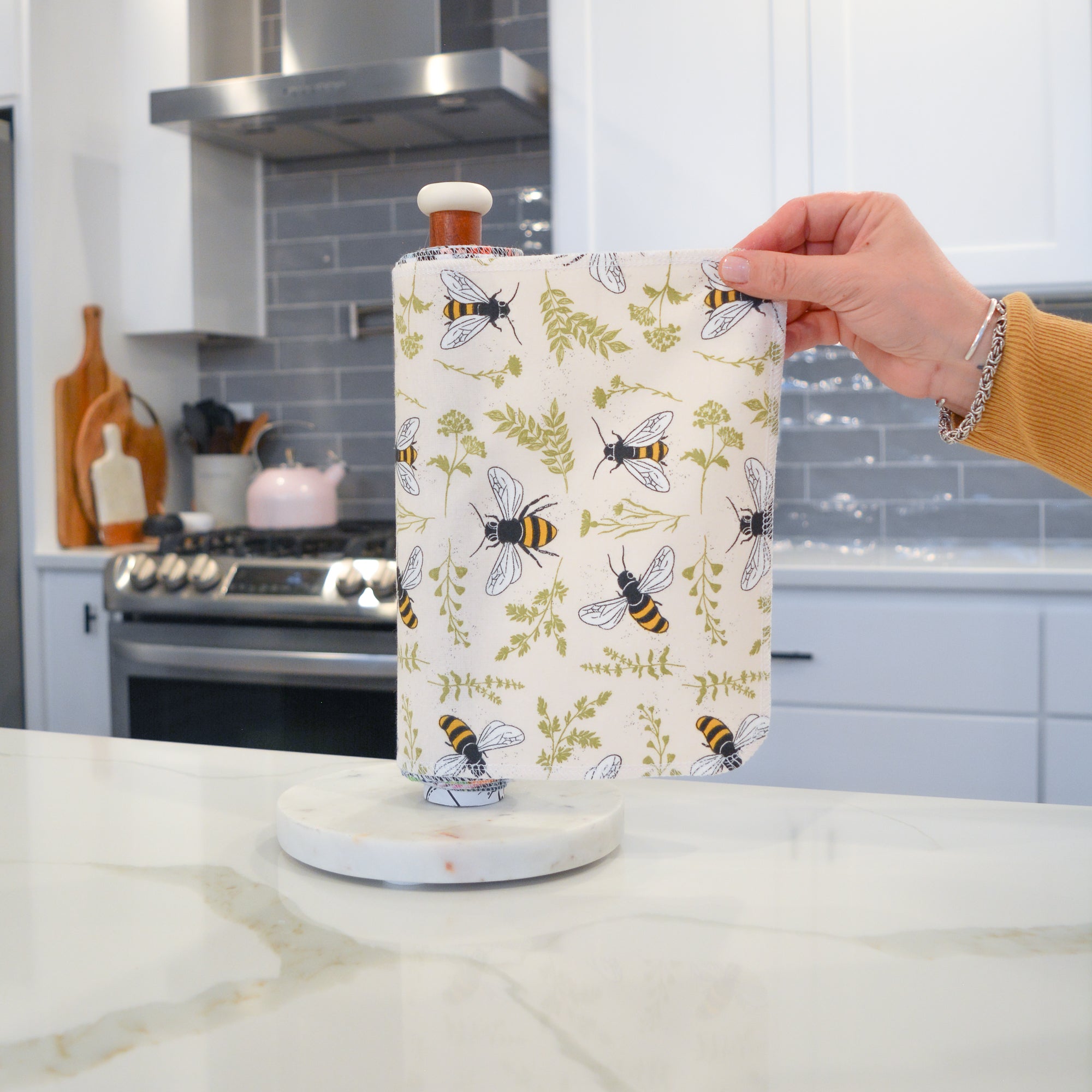Shows a hand pulling off one UNpaper® Towel in the Marley&#39;s Favorites pack in the Bees and Plants print. Marley&#39;s Monsters